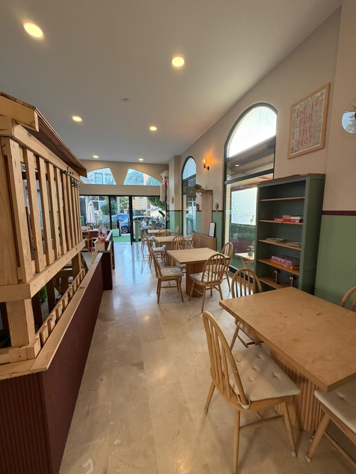 Kafe masalarından ahşap oyun evinin göründüğü salon